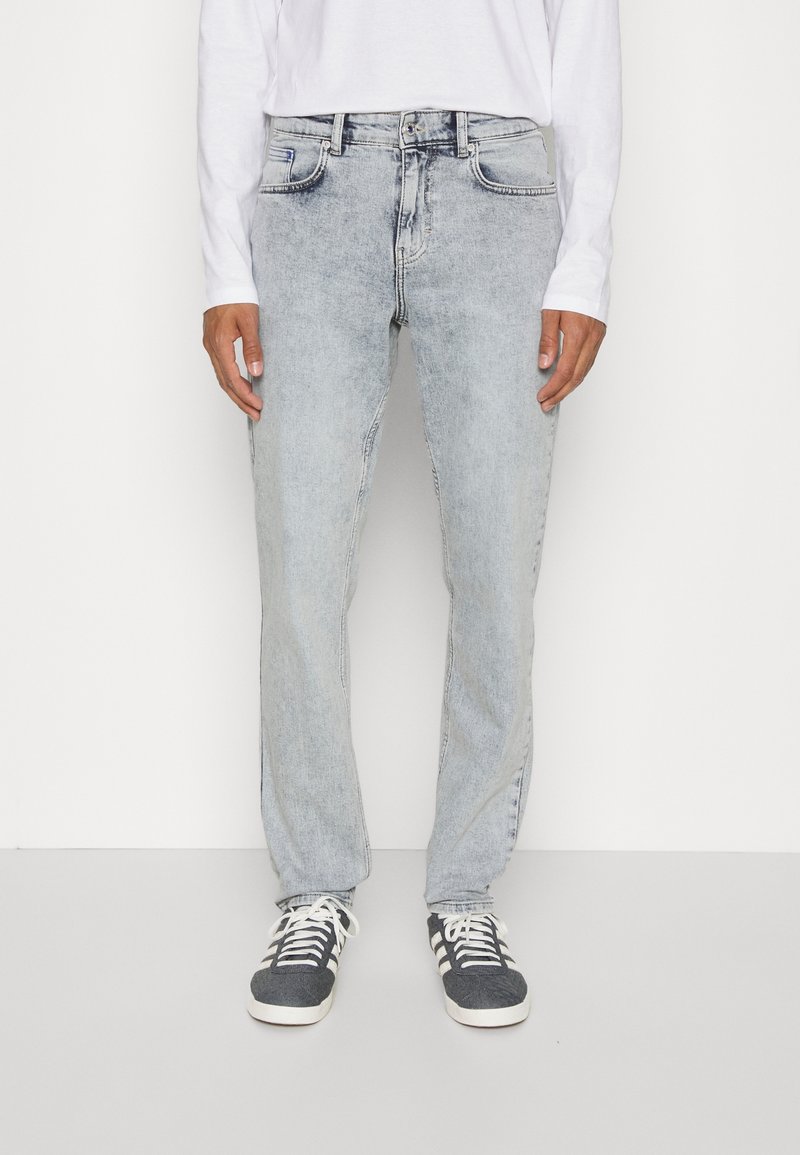 Ljusblå denimjeans med rak passform, utrustad med fem fickor och subtila blekningar. Kombinerat med svarta och vita sneakers.