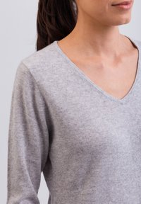 Maglione grigio a scollo a V in morbido tessuto a maglia, con maniche lunghe e vestibilità rilassata. Tessuto liscio con un lieve motivo melangiato.