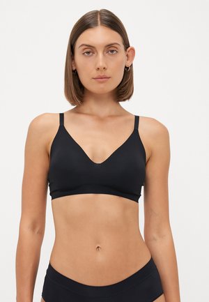 Black bralette with a deep V-neck, adjustable straps, seamless design, and soft fabric, featuring no visible hardware or embellishments.