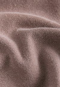 Tessuto rosa morbido e delicato con una superficie liscia e una leggera lucentezza. La superficie presenta un motivo a maglia fine e una leggera peluria.