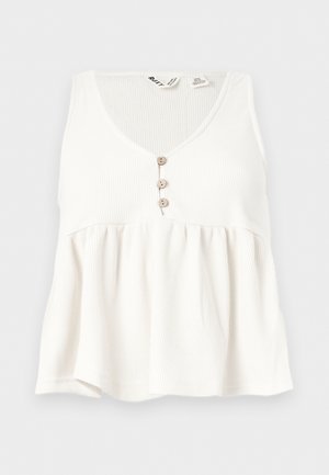 Bijeli rebrasti top bez rukava s V-izrezom i tri mala drvena gumba sprijeda.