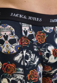 Nahaufnahme von navy-farbenen Boxershorts mit einem bunten Totenkopf- und roten Rosenmuster, schwarzem Bund mit der Marke "JACK & JONES".