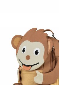 Affen-Themen-Rucksack mit einem braunen Stoffkörper, strukturierten Ohren, einem Cartoon-Gesicht und gestickten Details, ausgestattet mit einem Reißverschlussfach am Boden.