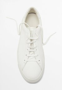Hvide sneakers lavet af glat læder, med rund tå, flade snører og en tekstureret gummisål med minimalistisk design.