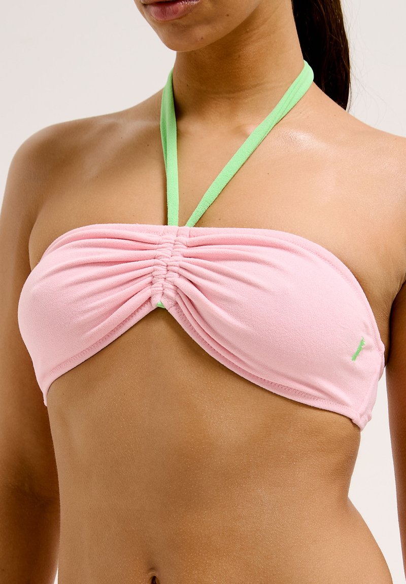 Haut de bikini bandeau rose avec un centre froncé, doté de bretelles vertes. Le matériau semble doux et extensible, adapté aux vêtements de bain.