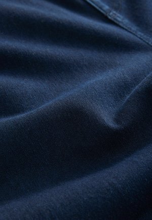 Donkerblauwe stof met een zachte, gladde textuur, met subtiele glans en zachte plooien, kenmerkend voor katoen of denim materiaal.