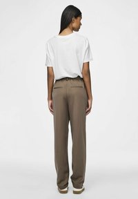Bequeme braune Hose mit einem Bund und zwei Gesäßtaschen, kombiniert mit einem schlichten weißen T-Shirt. Weiche Textur und minimalistisches Design.