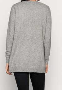 Šedý pletený svetr s dlouhými rukávy, žebrovanými manžetami a lemem, design s mírně prodlouženou zadní částí, měkká textura, minimalistický styl.