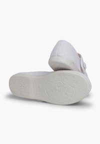 Weiße Textilschuhe mit einem schlichten Design, einem Knopfakzent und einer strukturierten Gummisohle, die mit floralen Mustern geprägt ist.