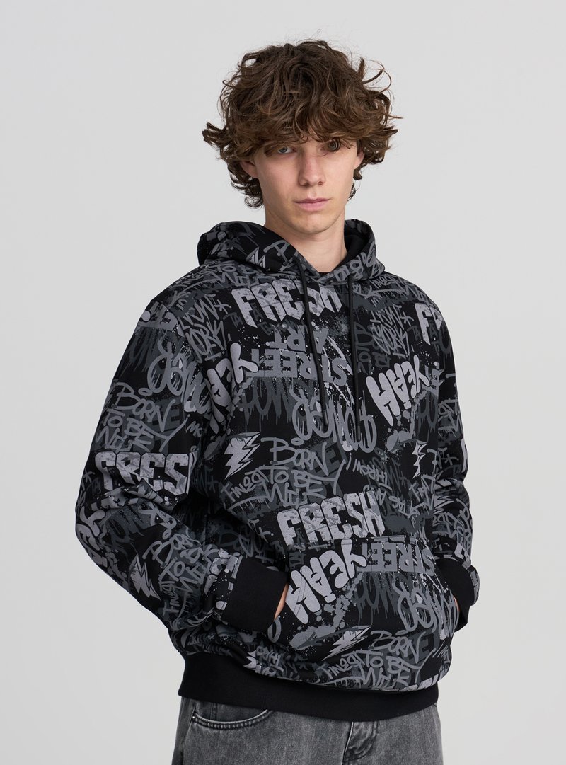 Czarna bluza z kapturem ozdobiona mieszanką szarych tekstów i grafik w stylu graffiti. Kaptur ze sznurkiem, ściągacze na rękawach i kieszeń z przodu. Miękka tekstura materiału.