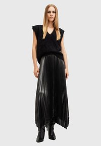 Black fuzzy knitted vest with a V-neck, paired with a pleated black leather maxi skirt, and black mid-calf fitted boots.