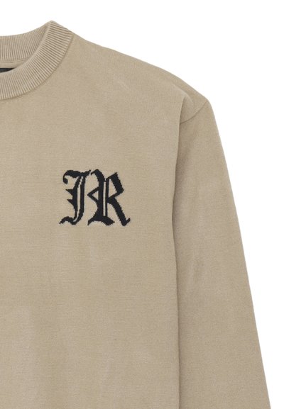 Maglione beige lavorato a maglia con scollo rotondo, caratterizzato da un logo "JR" ricamato in nero sul lato sinistro del petto. Tessuto morbido e vestibilità rilassata.