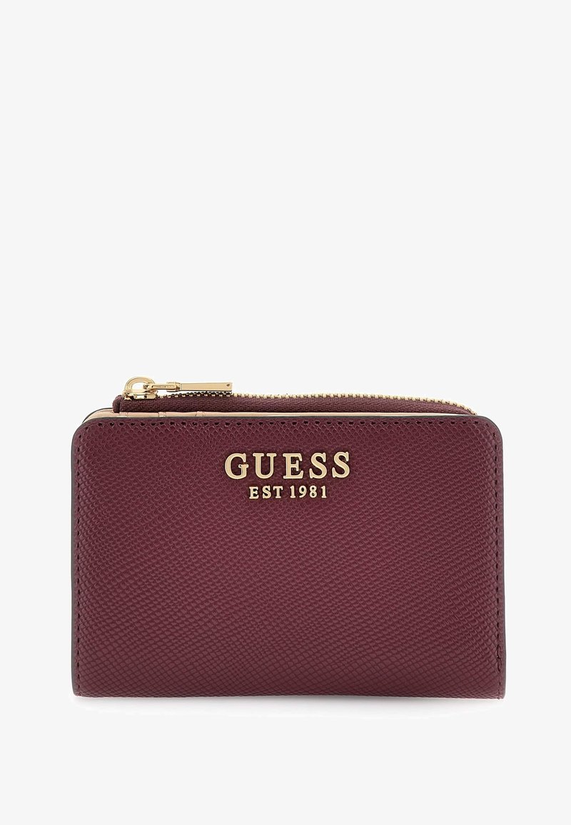 Cartera de cuero texturizado burdeos con cremallera dorada y el logotipo dorado "GUESS EST 1981" en la parte delantera.