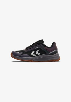 Zapatilla deportiva negra y púrpura oscuro con logo blanco en forma de chevron, diseño con cordones, entresuela gruesa gris y suela exterior marrón con dibujo.