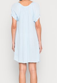 Jasnoniebieska sukienka z krótkim rękawem o luźnym kroju, z zakładkami z tyłu i zrolowanymi mankietami. Miękki, zwiewny materiał, długość do kolan.