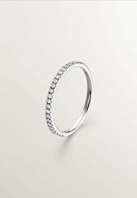 Anillo de plata que presenta una fila de pequeñas piedras redondas y claras a lo largo del borde superior, con una banda lisa y pulida y sutiles acentos en forma de estrella.