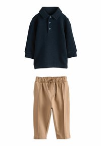 Marinefarbener Langarmpolo mit drei Knöpfen und Kragen, kombiniert mit beigen elastischen Hosen. Weicher Stoff mit glatter Textur.