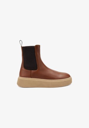 Bottine en cuir marron avec une semelle en caoutchouc beige à nervures, des panneaux latéraux élastiques noirs et une languette à l'arrière. Texture lisse et design épuré.