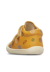 Gelbe Kleinkinderschuhe mit Sportball-Muster, ausgestattet mit Klettverschlüssen und einer weißen strukturierten Sohle, von der rechten Rückseite gezeigt.