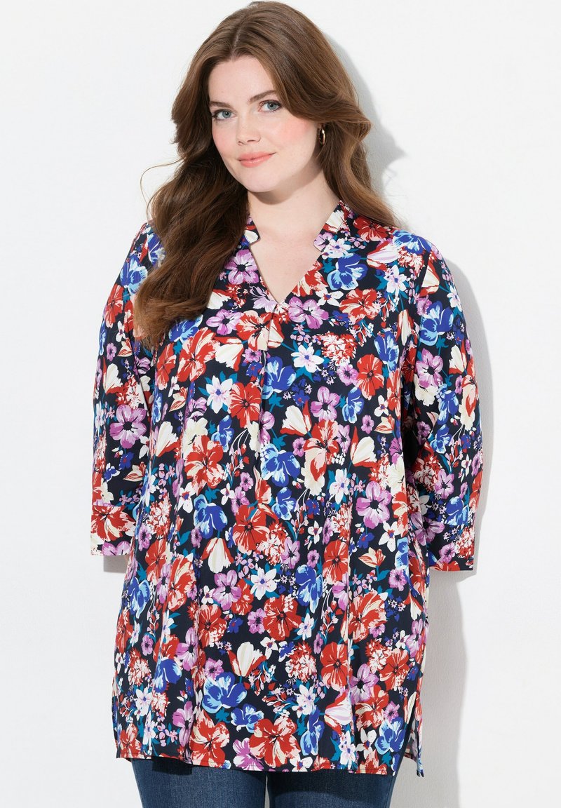 Blomsterbluse i navy med røde, pink og blå blomster. Har en v-hals og trekvartærmer. Lavet af letvægtsstof.