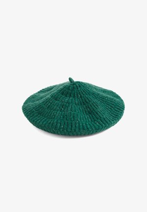 Boina de lana ribeteada verde con un centro ligeramente elevado y un pequeño detalle de nudo en la parte superior. Presenta un ala plana y una textura suave.