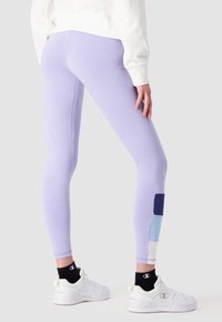 Leggings viola chiaro con un design aderente, caratterizzati da un motivo a blocchi di colore in blu e navy. Realizzati in un tessuto liscio e elasticizzato.