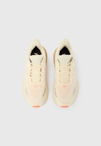 Αθλητικά παπούτσια σε ανοιχτό μπεζ χρώμα με επάνω μέρος από δίχτυ, υφή και λαστιχένια σόλα. Τα κορδόνια είναι στο ίδιο χρώμα, με πορτοκαλί λεπτομέρειες.