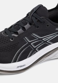 Scarpe sportive nere con tomaia in mesh e accenti grigi, lacci tondi e suola bianca imbottita contrassegnata "FFBlast+."