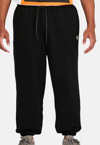 Pantalones de chándal negros con cintura ajustable, puños elásticos y un pequeño logo en la pierna izquierda. Fabricados en una tela suave y cómoda.