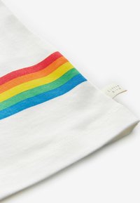 Balts kokvilnas T-krekls ar krāsainu horizontālu varavīksnes joslu sarkanā, oranžā, dzeltenā, zaļā un zilā krāsā; uz sāna ir neliela birka.