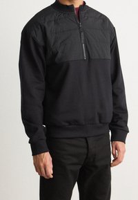 Sudadera negra con cuello de media cremallera, que presenta un panel superior suave y puños y dobladillo acanalados. Confeccionada con tejido mezclado para mayor comodidad.