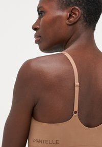 Nude padded bh met dunne verstelbare bandjes; zachte, gladde stof; met het logo "CHANTELLE" op de achterkant; naadloos ontwerp.