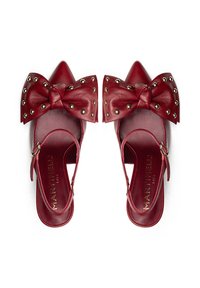 Zapatos de tacón estilo slingback de cuero rojo con punta afilada, gran lazo decorativo con remaches metálicos y correa al tobillo con detalle de hebilla.