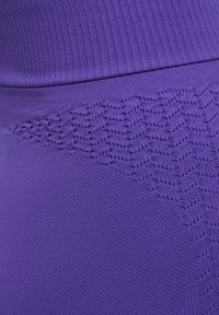 Tessuto activewear viola caratterizzato da un design testurizzato con una parte superiore a coste e un dettaglio a maglia nella porzione inferiore.