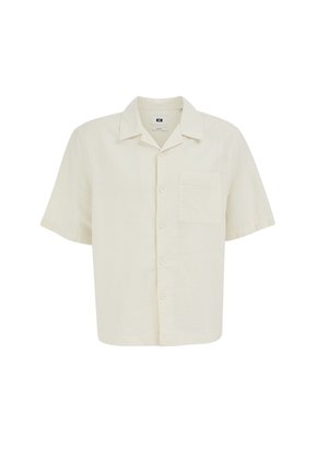 Camisa corta de manga corta color crema con botones, collar y un solo bolsillo en el pecho, exhibida sobre un fondo blanco.