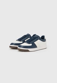 Ναυτικό και λευκό αθλητικό παπούτσι με υφασμένο δερμάτινο πάνω μέρος, στρογγυλή μύτη, επίπεδα κορδόνια και λαστιχένια σόλα. Διαθέτει πλευρική ρίγα σε λευκό χρώμα.