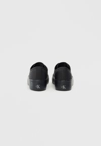 Pantofi slip-on din pânză neagră, cu vârful rotund, talpă plată din cauciuc și detaliu cu logo pe călcâi. Design minimalist cu parte superioară din textil.