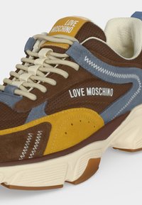 Chunky sneaker σε καφέ, μπλε και κίτρινο με μπεζ κορδόνια και λογότυπο "Love Moschino" στη γλώσσα και στην πλευρά.