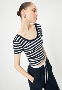 Stribet kortærmet top i navy og hvid med en scoop neckline og ribbet tekstur. Bæres sammen med mørke bukser med snoretræk.
