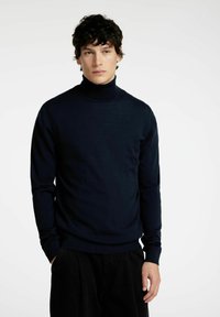 Mornarsko modra turtleneck pulover iz fine pletenine. Ima prilegajočo silhueto, rebraste manšete in gladko teksturo. Minimalističen dizajn.
