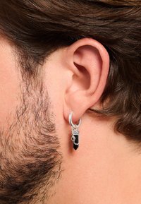 Silver hoop earring featuring a black crystal pendant with a pointed shape, accented by a delicate chain and geometric detail.