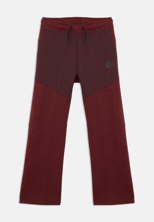 Bordo sporta bikses, izgatavotas no mīksta auduma, ar auklu jostasvietā, diagonāliem krāsu blokiem un pelēku Nike logo uz augšstilba.