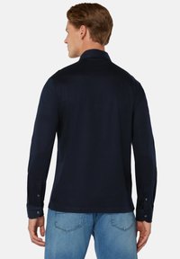 Marineblauwe longsleeve blouse van een katoenmix; met een klassieke kraag en knoopmanchetten. Getailleerde pasvorm met een zachte textuur.