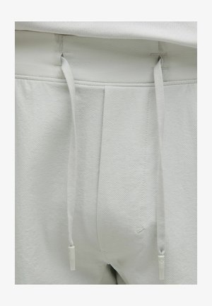 Lys grå joggere med en struktureret overflade, elastisk talje og snøre. Har syninger og et glat indre for.