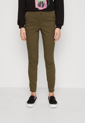 Chinos vert olive, coupe slim, fabriqués en tissu lisse, avec une taille standard et des poches latérales, associés à des chaussures noires à enfiler.