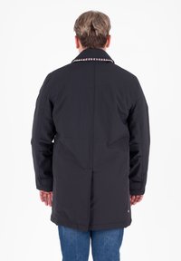 Cappotto lungo nero con taglio dritto, caratterizzato da un colletto con motivo a scacchi. Realizzato in tessuto liscio, presenta un design pulito ed elegante.