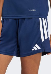 Αθλητικό σορτς σε ναυτικό μπλε χρώμα από υλικό που απομακρύνει την υγρασία, με τα τρία λευκά ρίγες της Adidas και το λογότυπο, καθώς και σχέδιο με χαλαρή εφαρμογή.