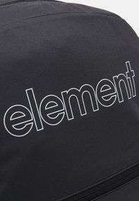 Zaino di tessuto nero con logo "element" bianco, texture liscia e compartimento con zip nella parte inferiore per ulteriore spazio di stoccaggio.