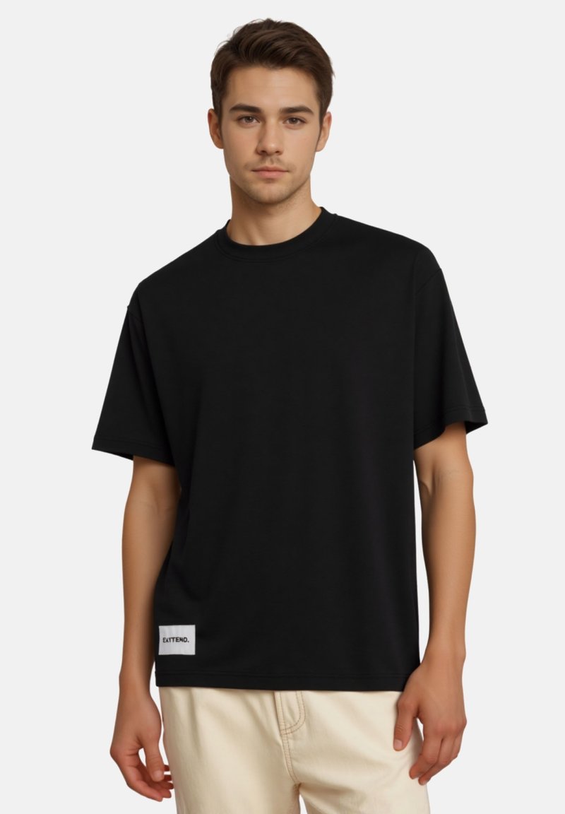 T-shirt nera a maniche corte realizzata in tessuto liscio, con collo rotondo e una piccola etichetta bianca in fondo. Silhouette semplice e classica.