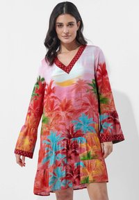 Rotes und pinkes Kleid mit tropischem Palmenbaumdruck, v-Ausschnitt, Glockenärmeln und gestuften Rüschen. Dekorativer roter Rand um den Ausschnitt.